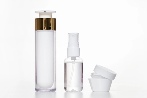 Drei leere Kosmetikverpackungen. Airless-Spender mit Goldrand, Sprühflasche und Cremetiegel, auf weißem Hintergrund.