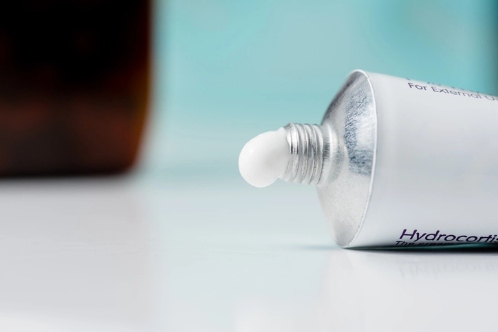 Aluminiumtube einer medizinischen Creme (Hydrocortison) mit weißer Creme an der Tubenöffnung.