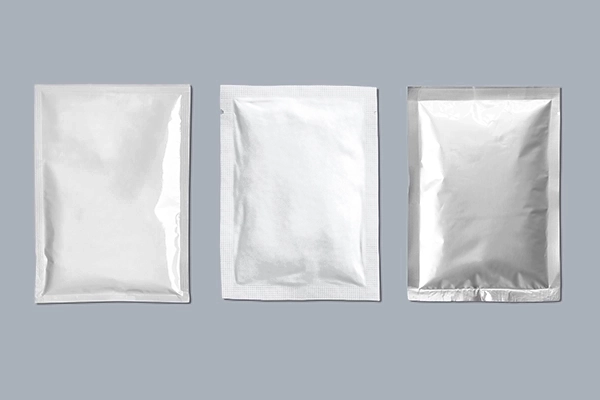 Drei versiegelte Sachets aus silbernem Folienmaterial auf grauem Hintergrund.